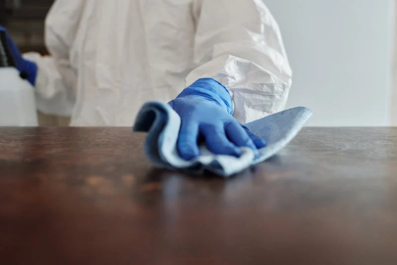 Professional cleaning operative in protective equipment wiping surface